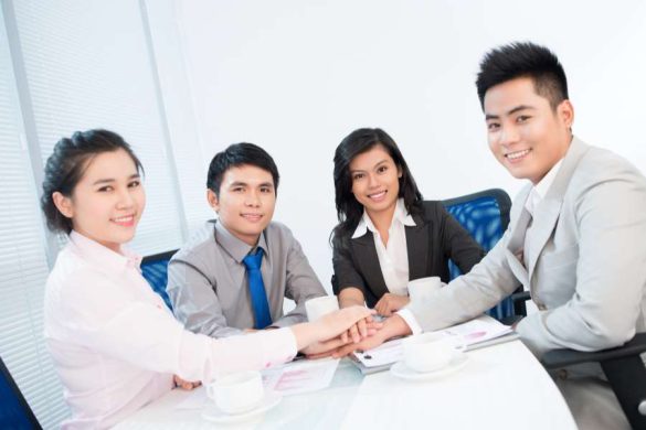 Équipe dynamique de conseillers de la Mutuelle Mieux-Etre joignant leurs mains en signe d'unité lors d'une réunion professionnelle