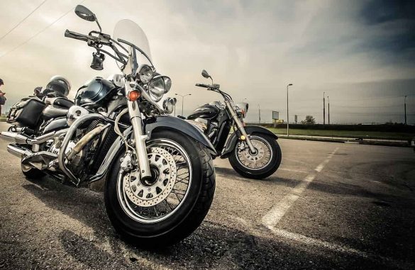 Deux motos custom avec une bulle haute moto visible au premier plan, garées sur un parking.