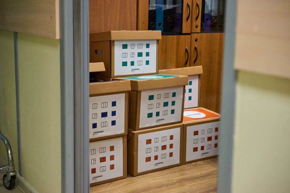 Cartons de déménagement empilés et marqués de gommettes de couleur, une astuce pour étiqueter ses cartons de déménagement par pièce de manière visuelle et ordonnée.