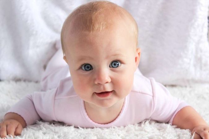 Un bébé aux yeux bleus regarde fixement la caméra, évoquant parfois les questionnements liés à la peur du noir chez les tout-petits.